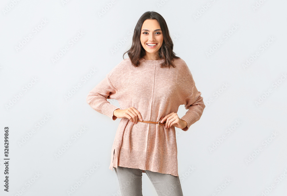 Beautiful young woman in warm sweater on light background Beautiful young woman in warm sweater on light background