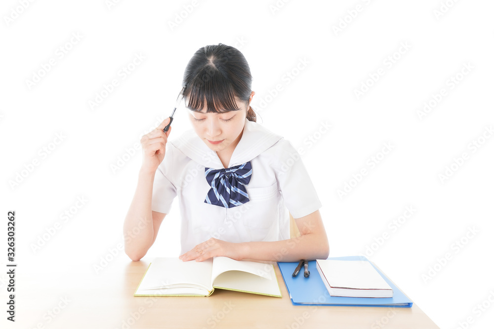 机で勉強をする制服姿の女子学生