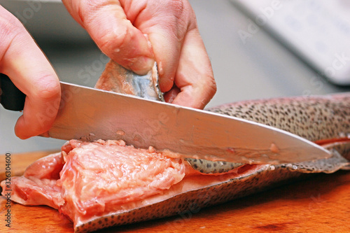 cook carving red fish on the board with a knife, prepare sushi, horizontal, background
