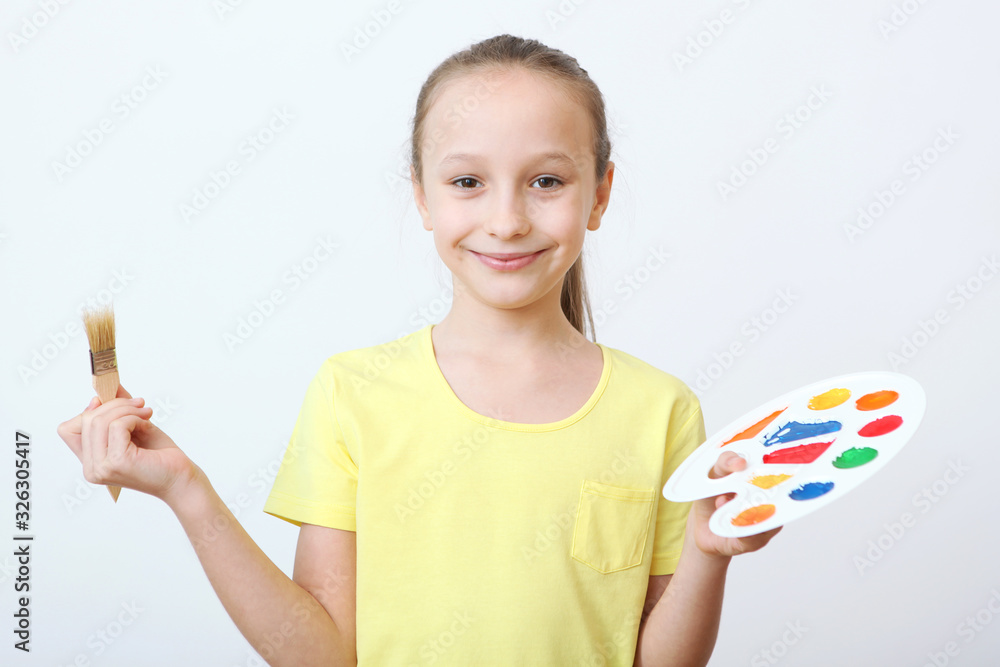 Cute happy girl with a palette for paints and a brush on a light background. Cute happy girl with a palette for paints and a brush on a light background.