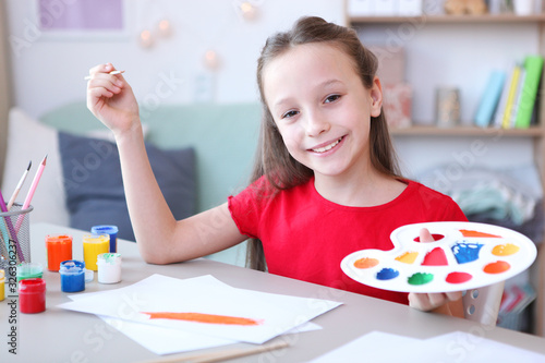 Cute little girl draws paints at home.