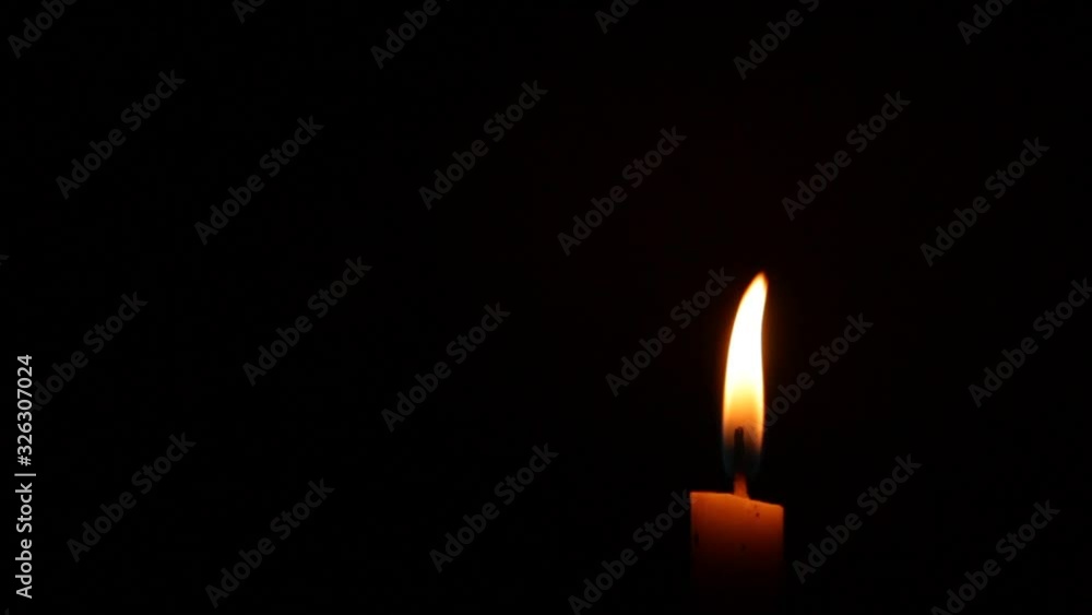 Close-up of a Candlelight Isolated on a Black Background, candlelight moves in the wind Close-up of a Candlelight Isolated on a Black Background, candlelight moves in the wind