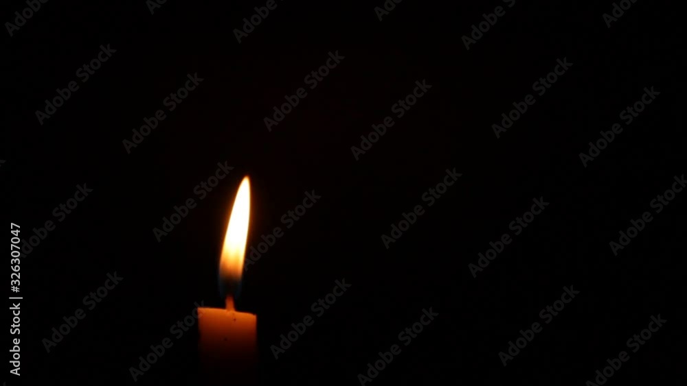 Close-up of a Candlelight Isolated on a Black Background, candlelight moves in the wind Close-up of a Candlelight Isolated on a Black Background, candlelight moves in the wind