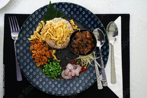 Close up dish of Shrimp paste fried rice served with mixed vegetables and sweetened pork