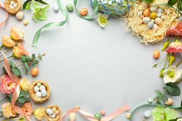 Happy Easter concept with easter eggs in nest and spring flowers. Easter background with copy space. Flat lay