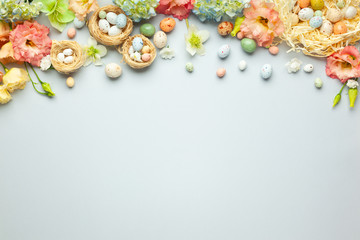 Happy Easter concept with easter eggs in nest and spring flowers. Easter background with copy space. Flat lay.
