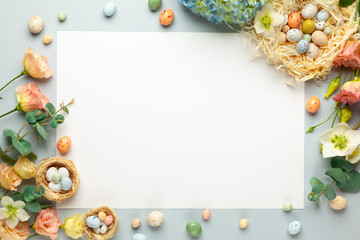 Happy Easter concept with easter eggs in nest and spring flowers. Easter background with copy space. Flat lay