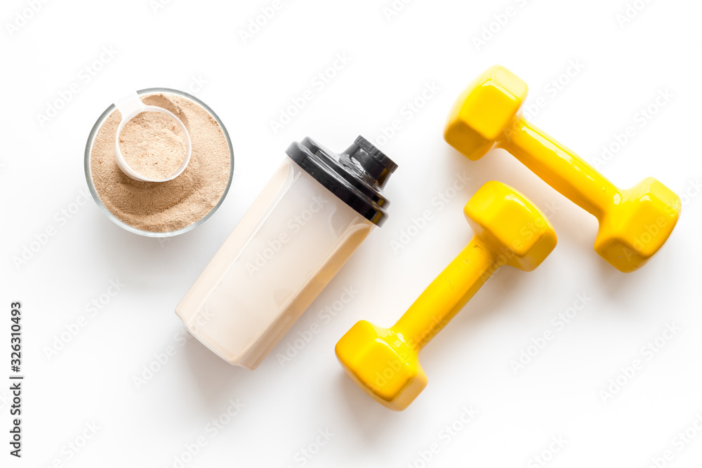 Sport nutrition. Whey protein, shaker, dumbbells on white background top-down flay lay Sport nutrition. Whey protein, shaker, dumbbells on white background top-down flay lay