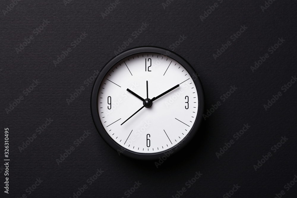 Modern balck alarm clock on black background. Top view, minimal styled. Modern balck alarm clock on black background. Top view, minimal styled.