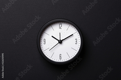 Modern balck alarm clock on black background. Top view, minimal styled.