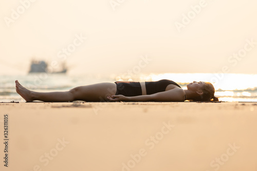 Vacation of Beautiful Attractive Asian woman relaxing in yoga Savasana pose on the beach with beautiful sea in Tropical island,Feeling comfortable and relax in holiday,Vacations Concept photo