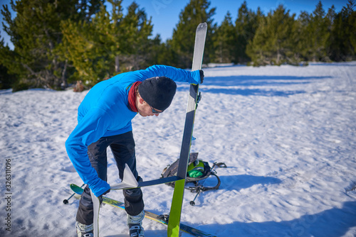 Person sticking climbing skins on splitboard on the snow.