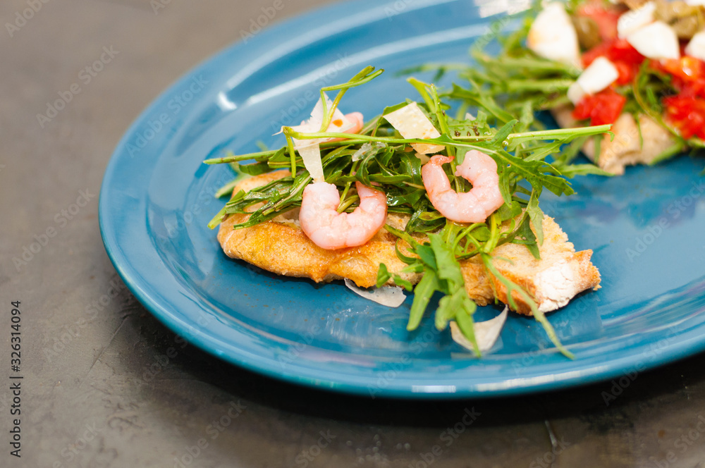 Bruschetta with shrimp, arugula, tomatoes, cheese and sauce, close-up, high Italian cuisine Bruschetta with shrimp, arugula, tomatoes, cheese and sauce, close-up, high Italian cuisine