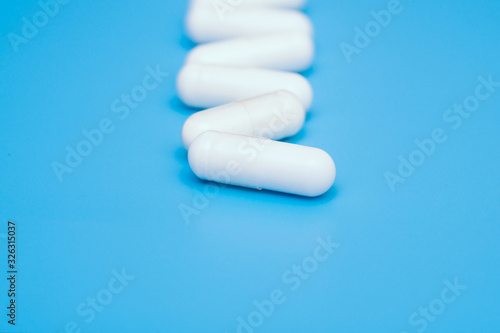 white capsule pills on blue background