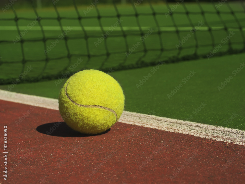Tennis ball on the court and the net on the background. A sports concept