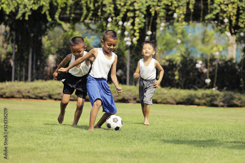 Asian boys playing football on the lawn with fun..