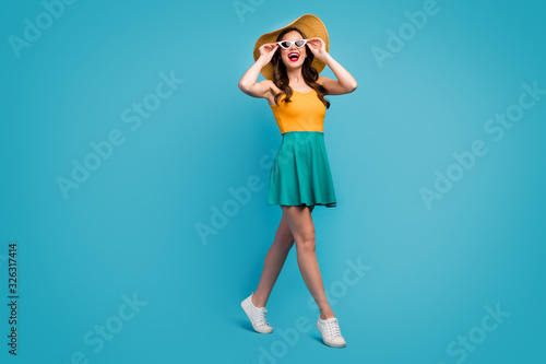 Full length photo candid cute sweet girl enjoy spring free time vacation look incredible excursion sights touch hands spectacles wear bright singlet sunhat shoes isolated blue color background