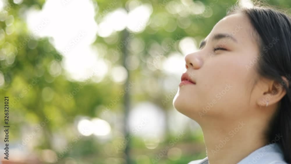 Close up portrait of young asian girl relaxed enjoying peaceful sunset and looking up exhaling fresh air relaxing at a public park on the beautiful summer sunset. Close up portrait of young asian girl relaxed enjoying peaceful sunset and looking up exhaling fresh air relaxing at a public park on the beautiful summer sunset.