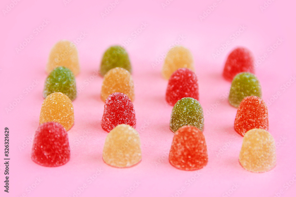 round sweet multi-colored candy marmalade in sugar sprinkles on pink background round sweet multi-colored candy marmalade in sugar sprinkles on pink background