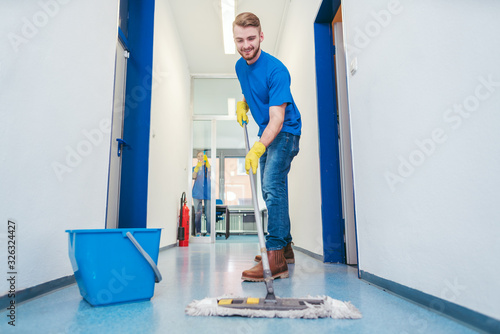 Cleaner man mopping the floor in a hall photo