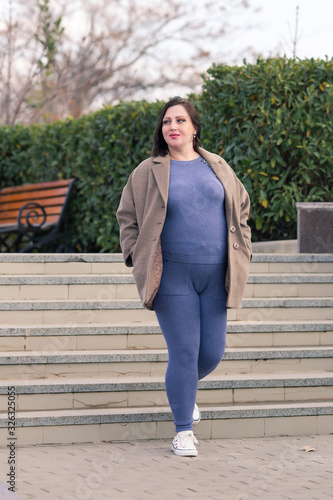 Expectant mother in sportswear and cloth jacket resting in park