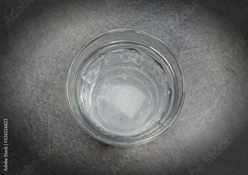The glass is half full of water on grey table top view with space for text, filtered image