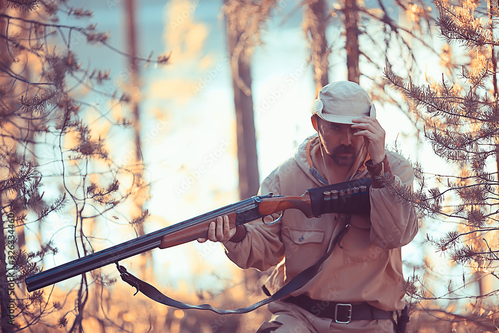 Naklejka premium hunting man / hunter with a gun hunting in the autumn forest, yellow trees landscape in the taiga