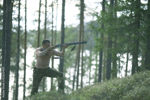 man goes hunting forest summer / landscape in the forest, huntsman with a hunting rifle hunts