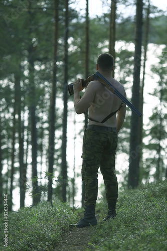 man goes hunting forest summer / landscape in the forest, huntsman with a hunting rifle hunts © kichigin19