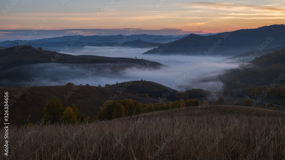 Morning fog in a mountain valley before sunset. Autumn Altai.