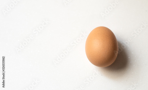 Brown chicken egg with shadow on white background
