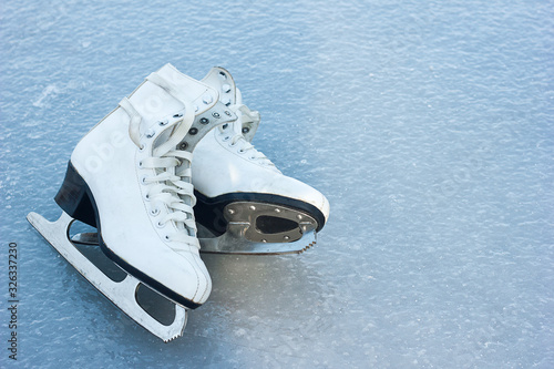 old white figure skates lie on ice, winter outdoor activities, sports health in winter, space for text	