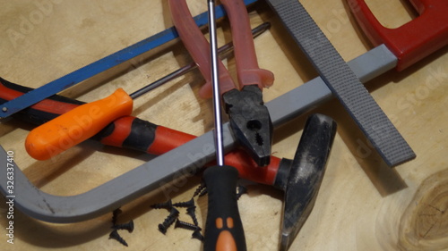 tools: hammer, hacksaw, pliers, screwdriver on wooden flooring