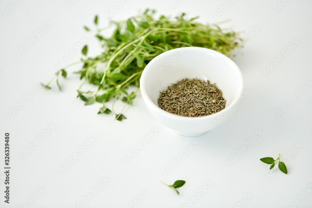 greens, culinary and flavoring concept - bunch of fresh thyme herb and dry seasoning in cup on white background