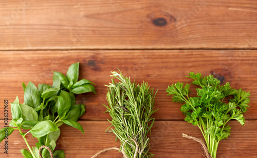 greens  spices or medicinal herbs concept - bunches of parsley  basil and rosemary on wooden boards