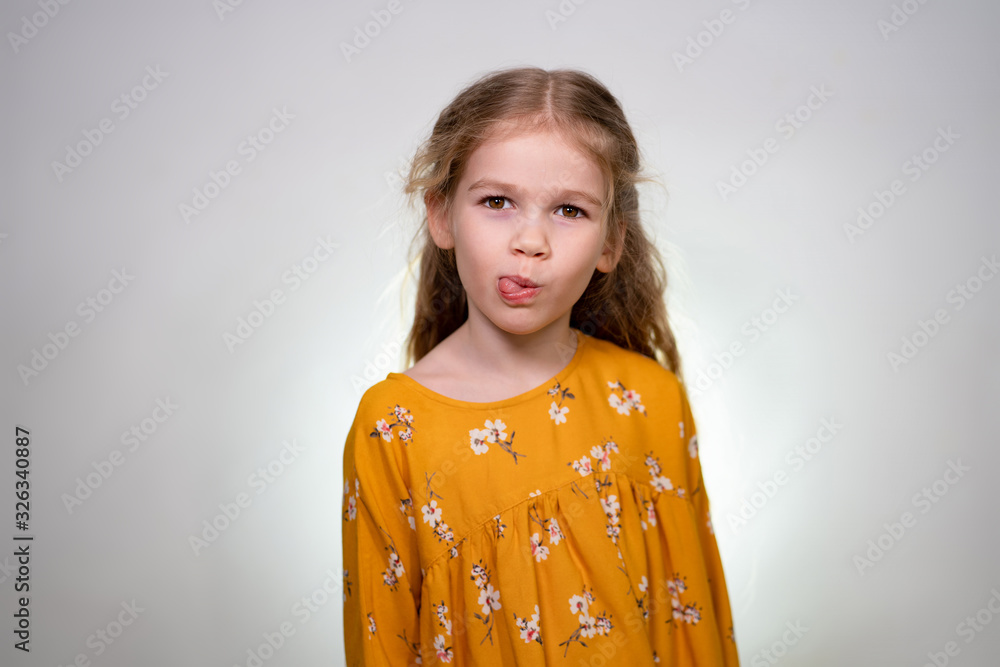 little girl shows her tongue, white wall little girl shows her tongue, white wall