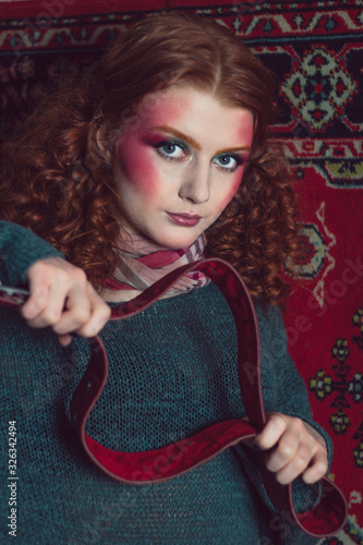 Beautiful red-haired curly girl holds a belt.. photo