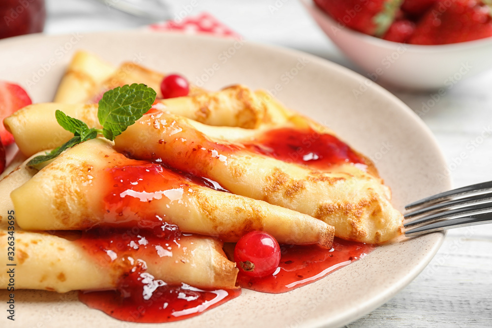 Delicious thin pancakes with strawberries and jam on table, closeup Delicious thin pancakes with strawberries and jam on table, closeup