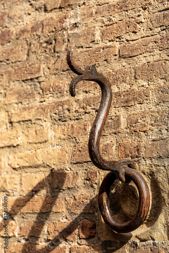 Ancient wrought iron ring in the shape of a snake or dragon for tying with rope the animals, horses, mules or cattle. Bologna downtown, Emilia-Romagna, Italy, Europe