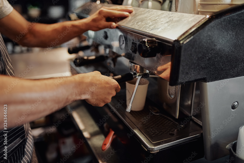 Closeup of male waiter hands making coffee from machine in cafe Closeup of male waiter hands making coffee from machine in cafe