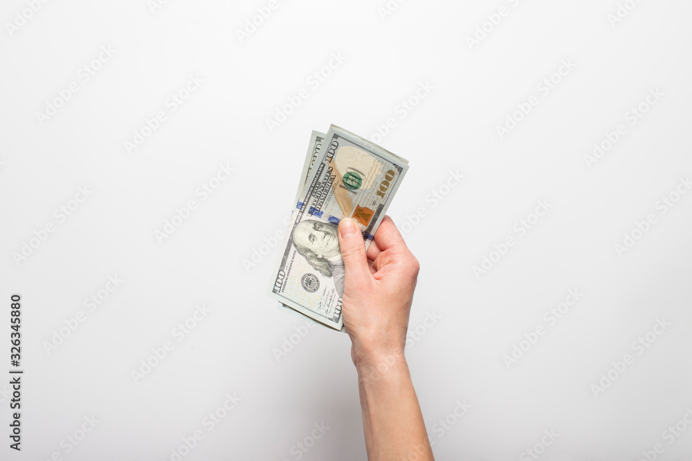 Female hand holds, counts money, dollars on a light background. Concept of pay, wealth, purchase, taxes. Banner. Flat lay, top view Female hand holds, counts money, dollars on a light background. Concept of pay, wealth, purchase, taxes. Banner. Flat lay, top view