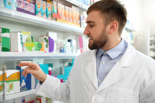Professional pharmacist near shelves in modern drugstore
