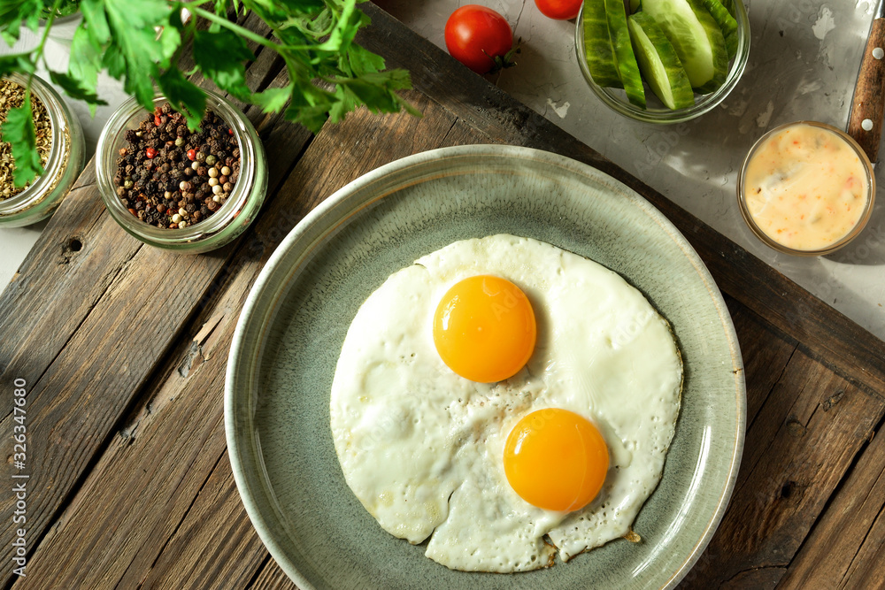 Tasty fried eggs for breakfast. Fried eggs in a plate on a wooden table background, top view. Tasty fried eggs for breakfast. Fried eggs in a plate on a wooden table background, top view.