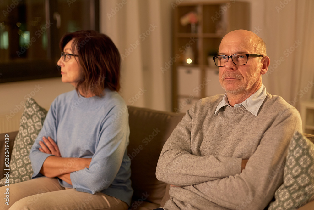 relationships difficulties, problem and people concept - unhappy senior couple sitting on sofa at home relationships difficulties, problem and people concept - unhappy senior couple sitting on sofa at home