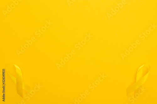 Top view of yellow ribbons on colorful background, international childhood cancer day concept photo