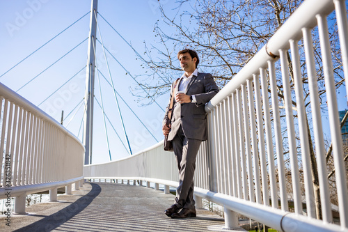 Middle aged businessman waiting on a bridge with a coffee