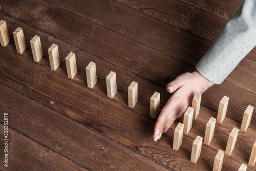 Businesswoman protecting dominoes from falling