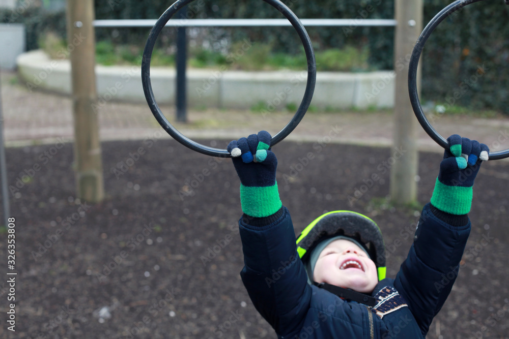 Obraz premium Child hanging on the gymnastic rings on the playground