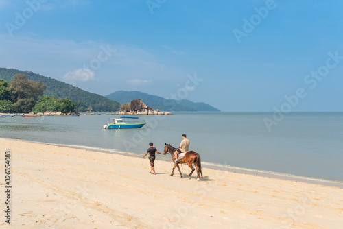 Horse riding at the Batu Ferringhi beach on the island of Penang. The small town is the prime beach destination in Penang among locals and tourists