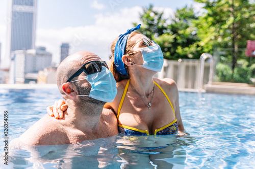 tourists wear the protective mask in the pool to protect themselves from the coronavirus © carles